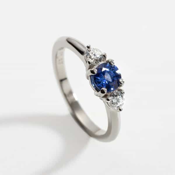 Platinum Ring, 0.58ct round sapphire (5mm in diameter) in a four claw setting and 2 x 3mm diamonds (0.2ct diamond total)