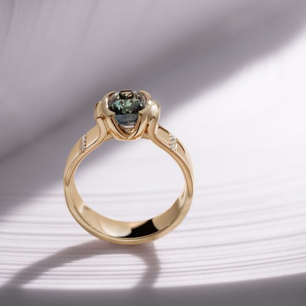 18ct yellow gold signature demi flush ring set with a 2.22ct teal blue cushion sapphire and 8 x pave set diamonds, €5,350